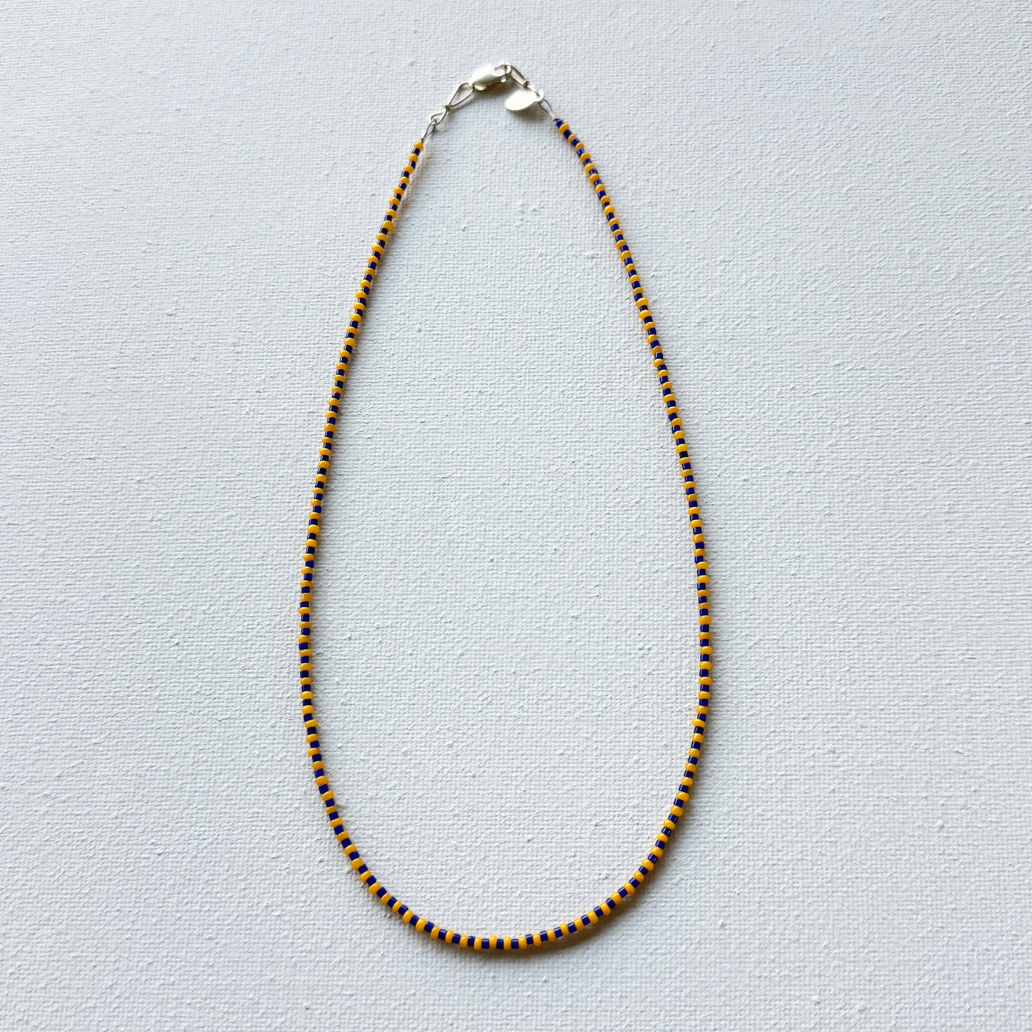 Necklace with blue and gold beads on a light gray background