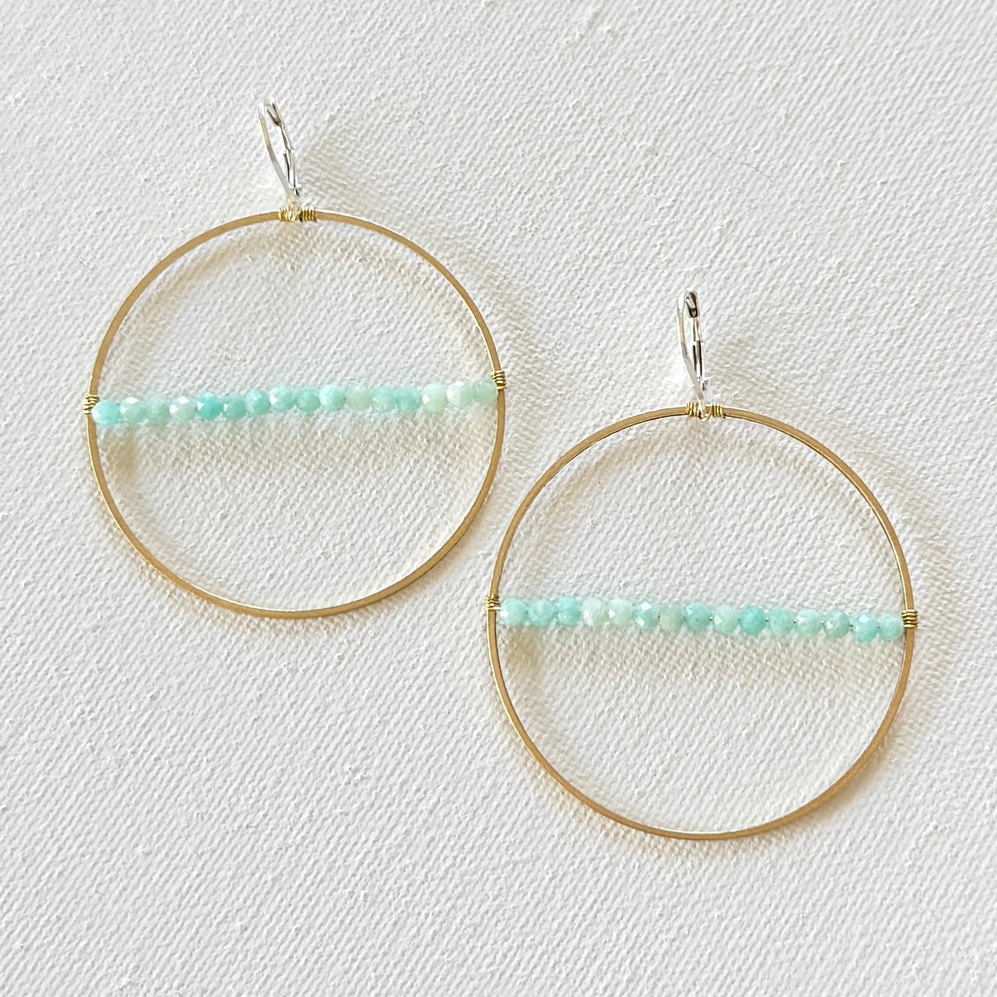 Gold hoop earrings with turquoise beads on a light background