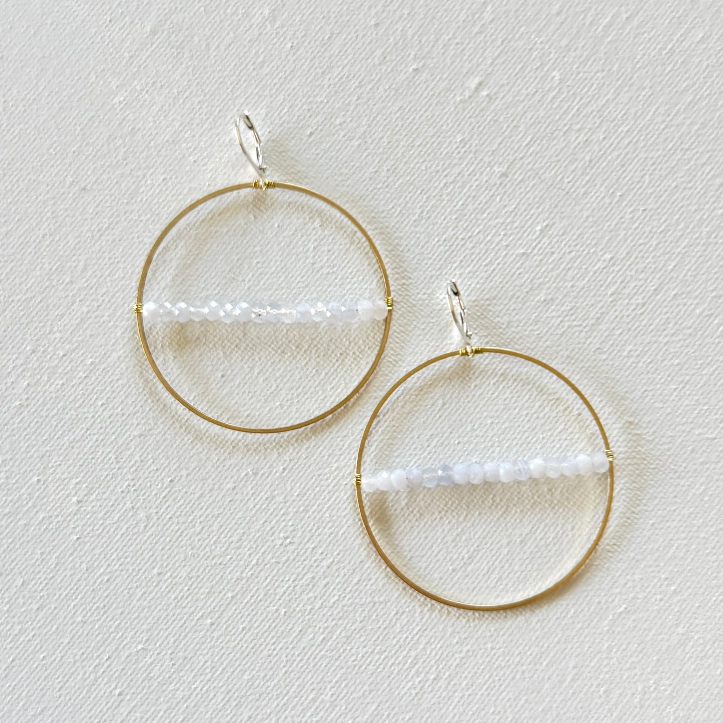 Gold hoop earrings with a central bar on a light gray background