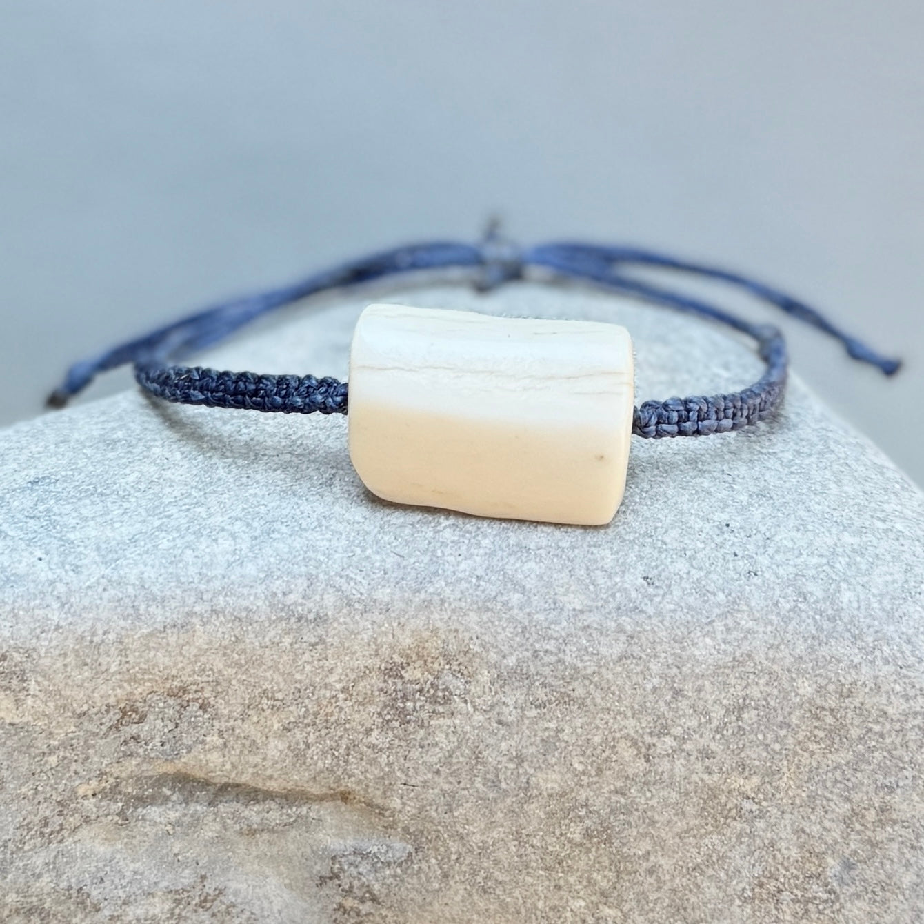 Bracelet with a square bone-like charm on a textured surface