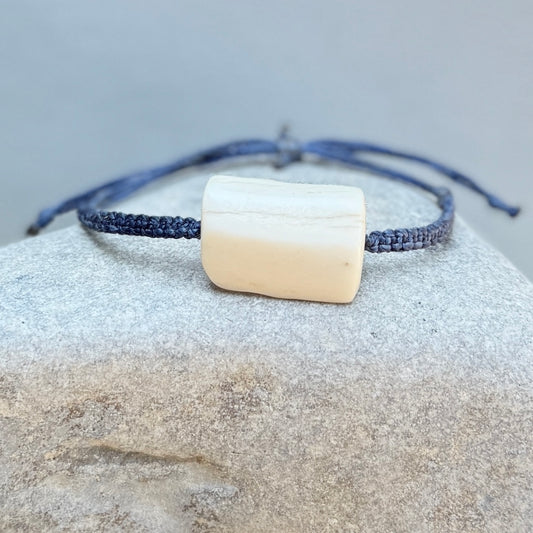 Bracelet with a square bone-like charm on a textured surface