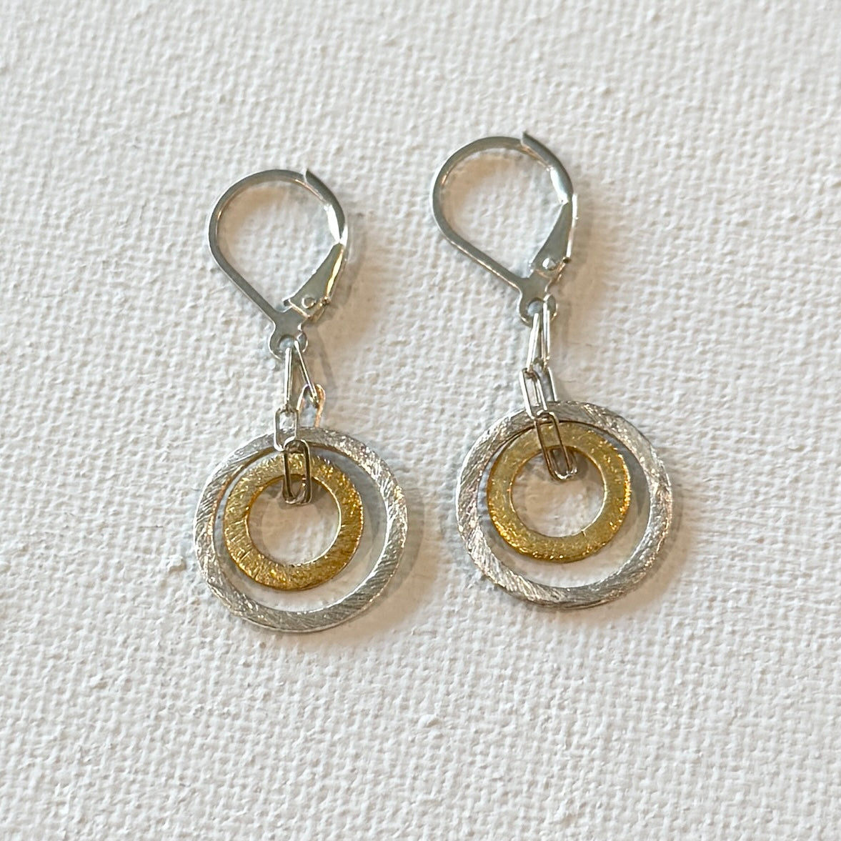 Sterling silver lever back ear wires interlocked with tiny sterling silver chain and two brushed circles one vermeil over lay of sterling silver and one sterling silver.