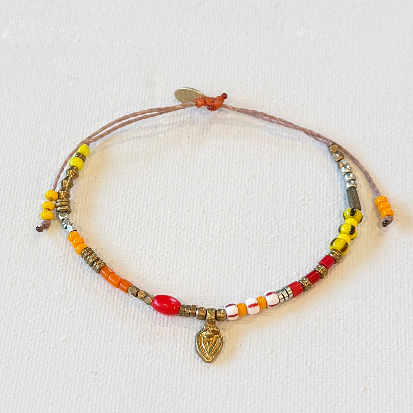 red, yellow and orange glass beads mixed with brass and silver beads on a natural cord. One size fits all
