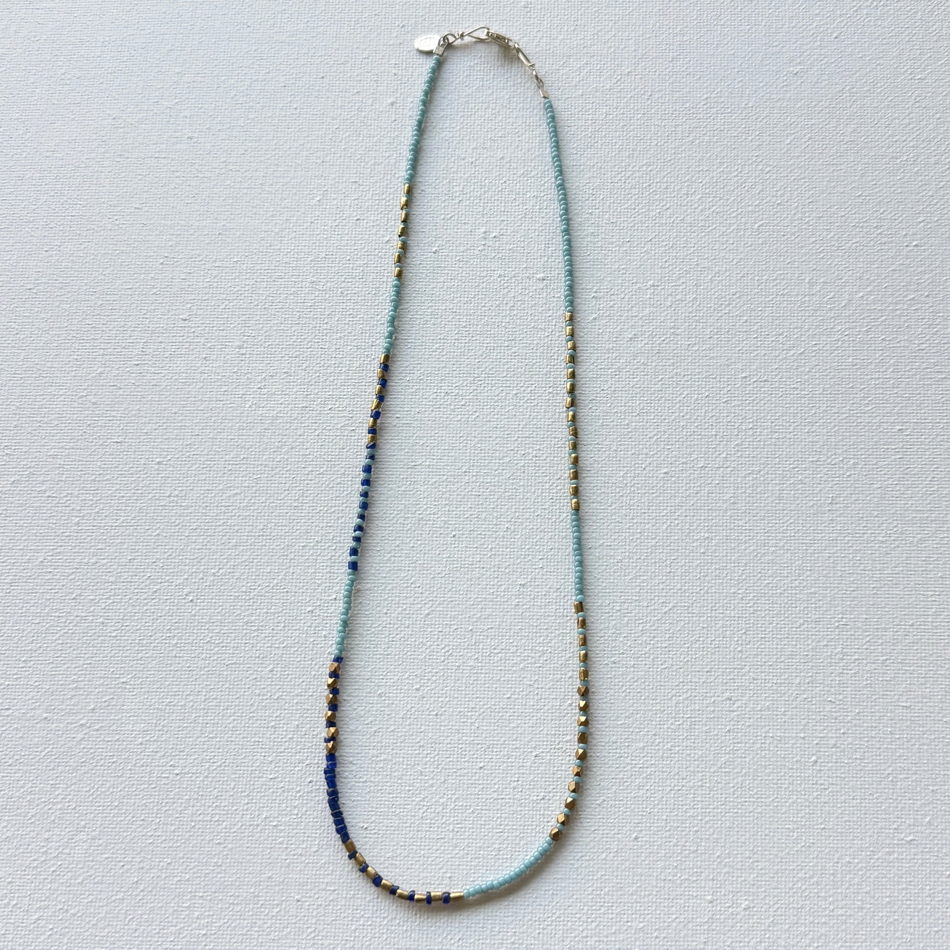 Necklace with blue and gold beads on a light gray background
