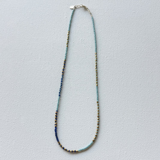 Necklace with blue and gold beads on a light gray background