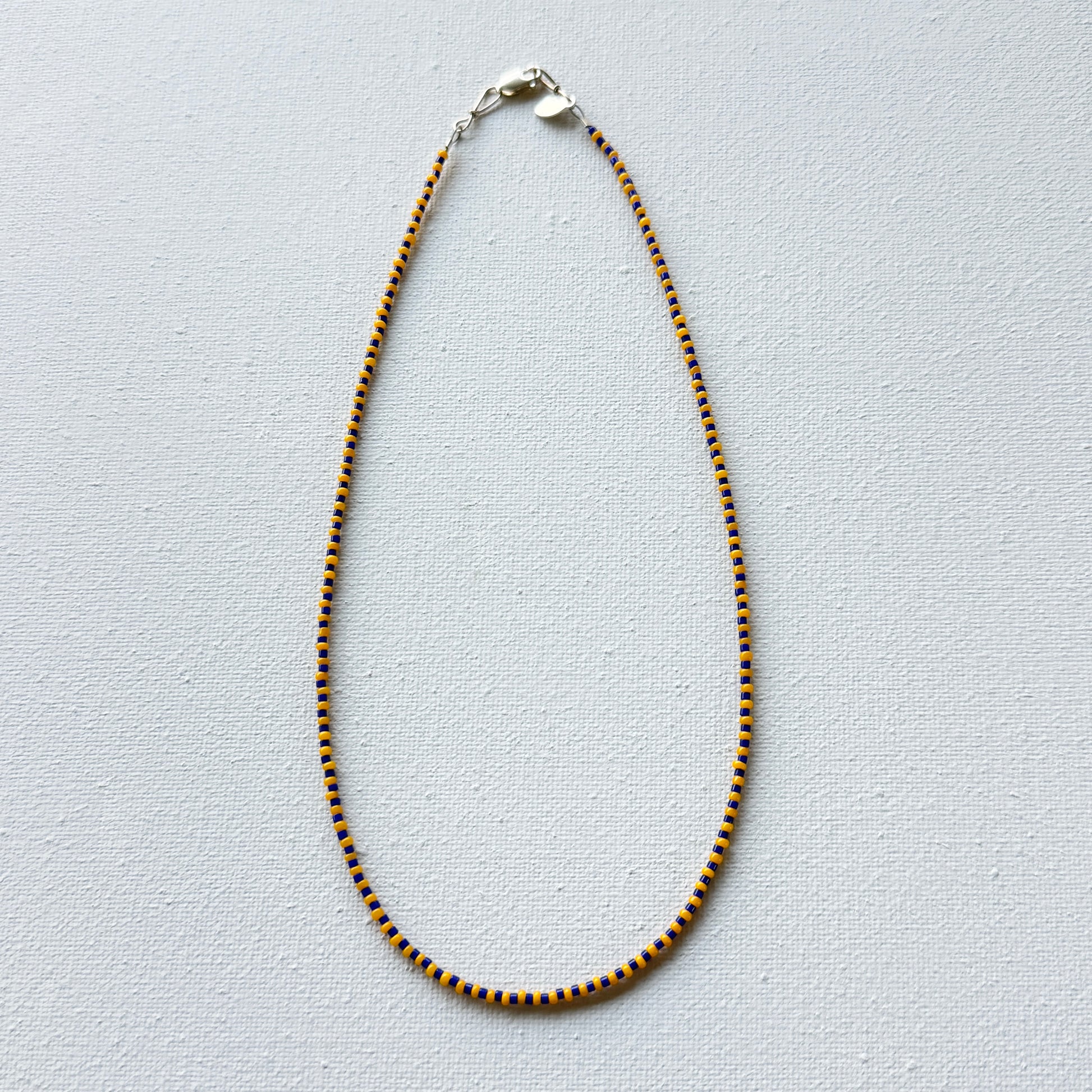 Necklace with blue and gold beads on a light gray background