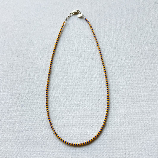 Necklace with blue and gold beads on a light gray background