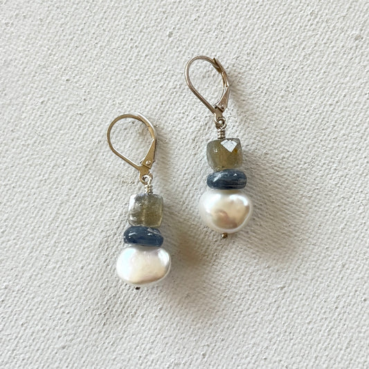 Pair of earrings with pearls and gemstones on a light gray background