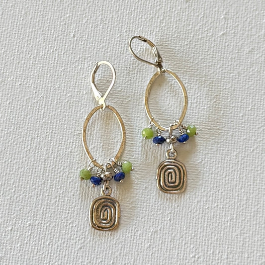 Pair of silver earrings with circular designs and colorful beads on a light gray background