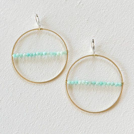 Gold hoop earrings with turquoise beads on a light background