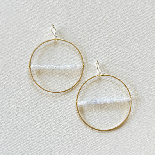 Gold hoop earrings with a central bar on a light gray background