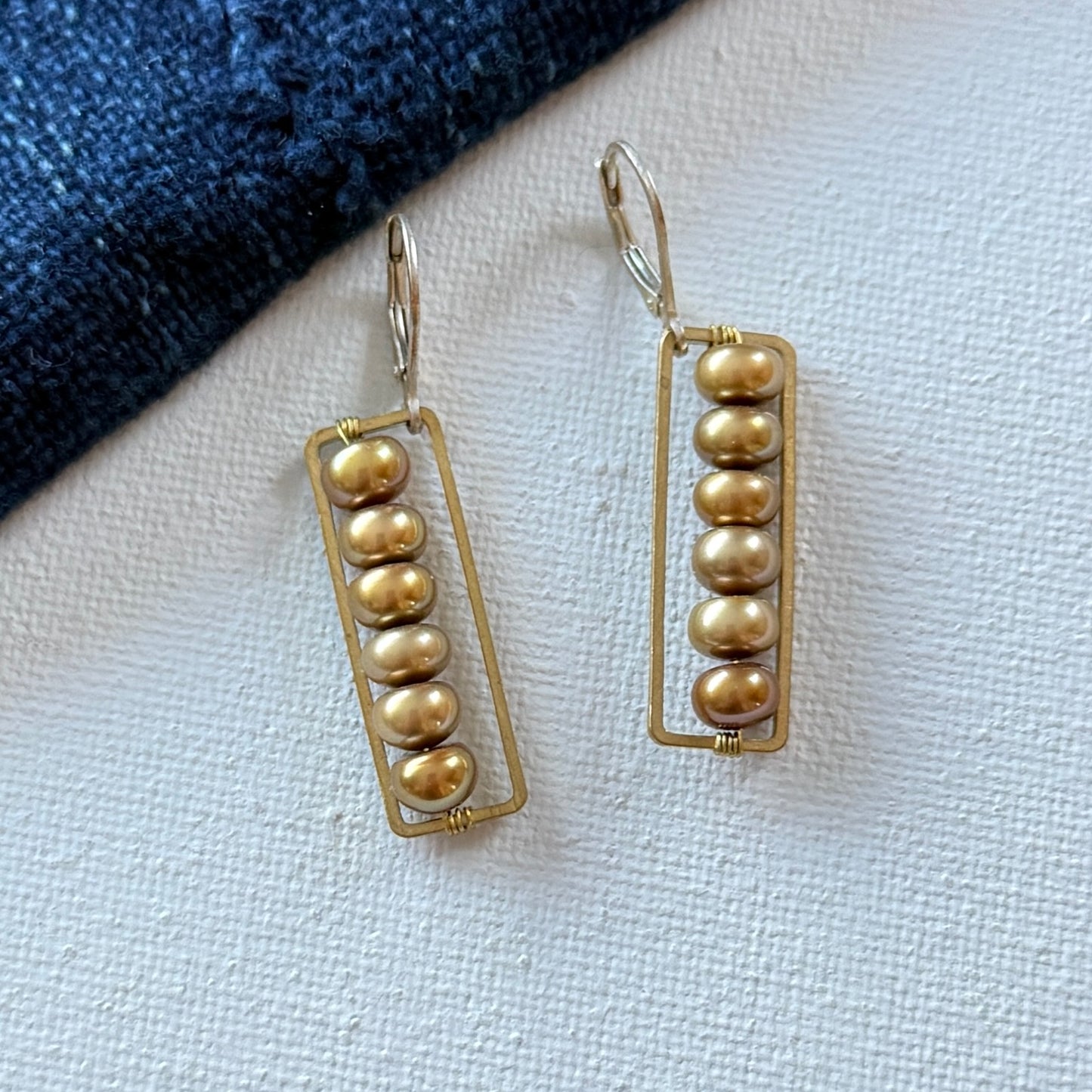 gold frames interlocking rust colored freshwater pearls and sterling silver lever back ear wires.