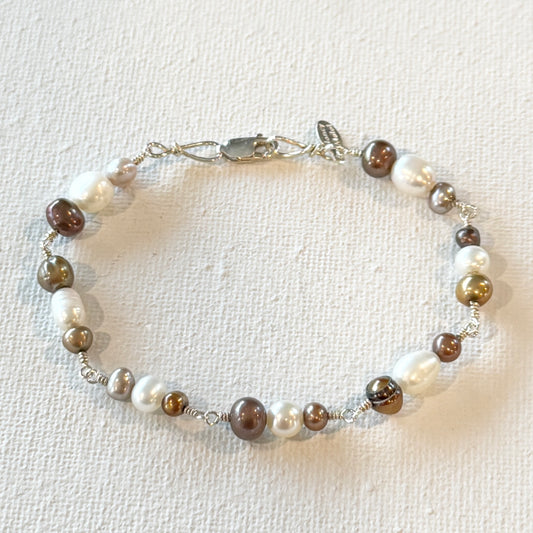 hand linked sterling silver with a sterling silver lobster clasp and a hand stamped signature tag. Interlocking white and brown/ rust fresh water pearls in all different shapes and sizes/
