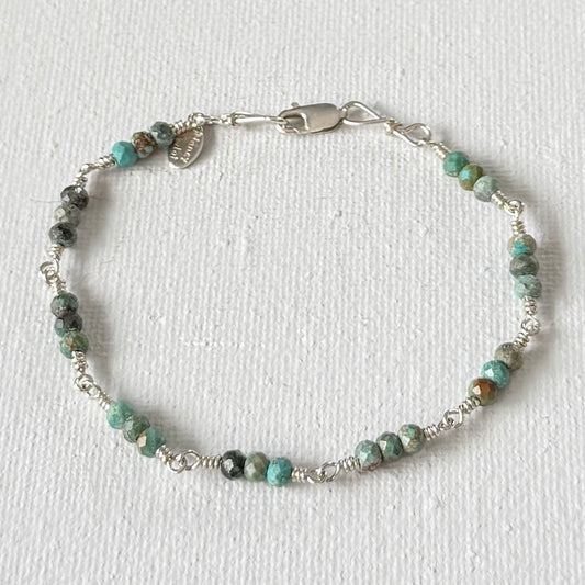 Beaded bracelet with silver clasp on a white background with faceted green turquoise beads in clusters of 3.
