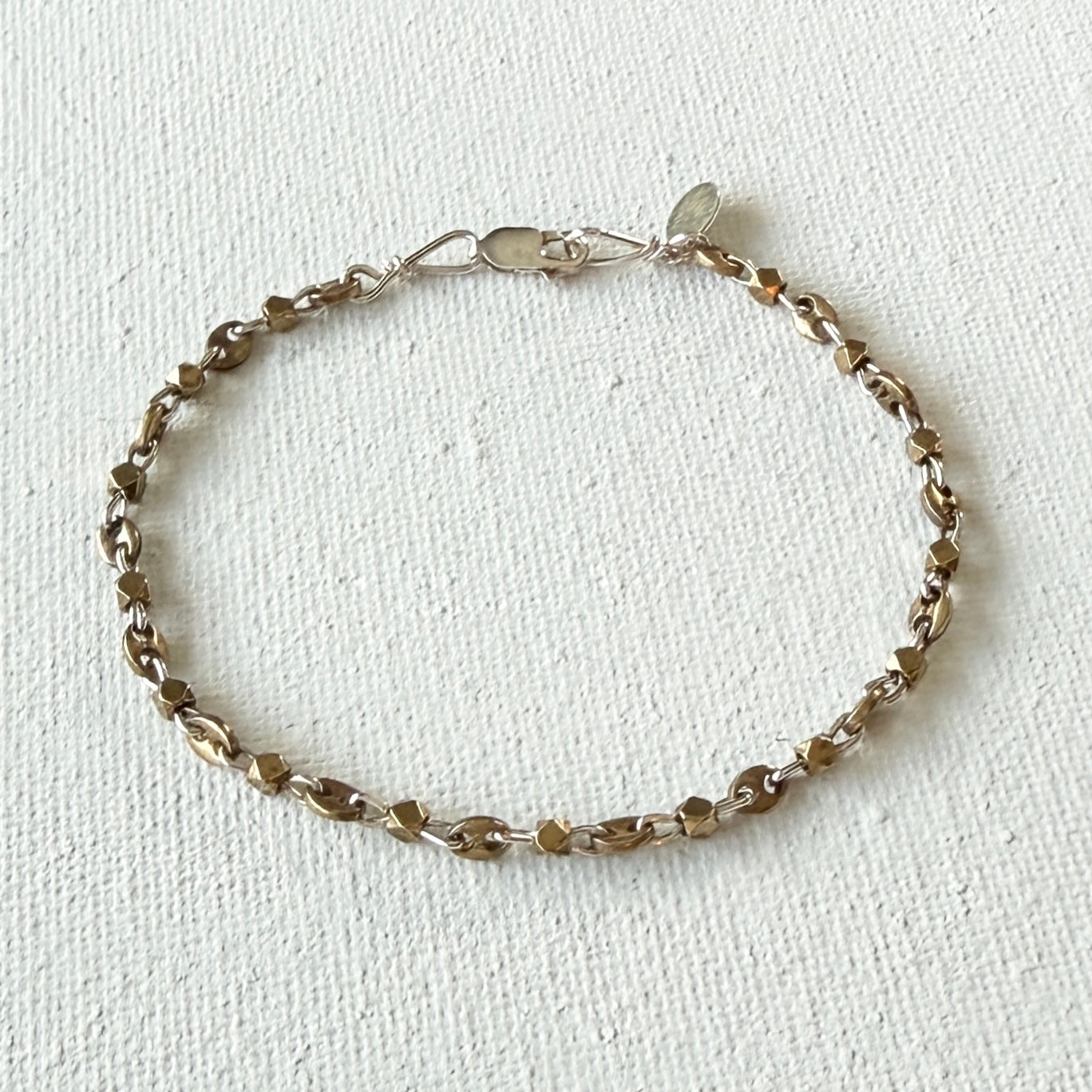 Silver  and brass bracelet on a light beige background.