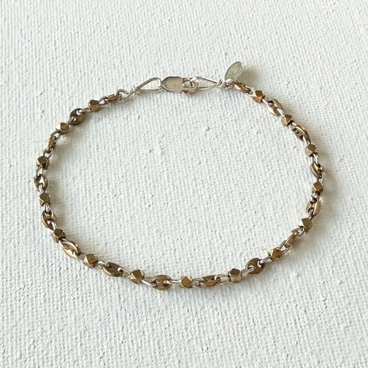 Silver  and brass bracelet on a light beige background.