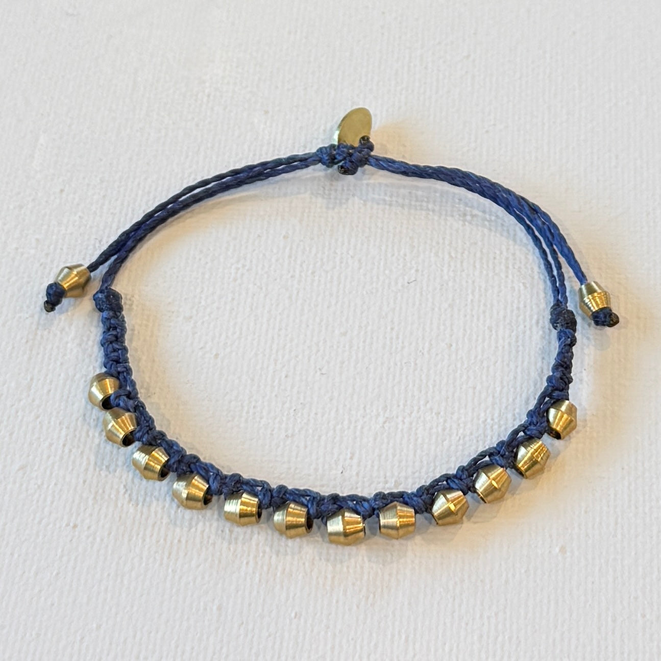 navy adjustable waxed nylon interlocking brass shapes. One size fits all. This bracelet has a nice weight to it.