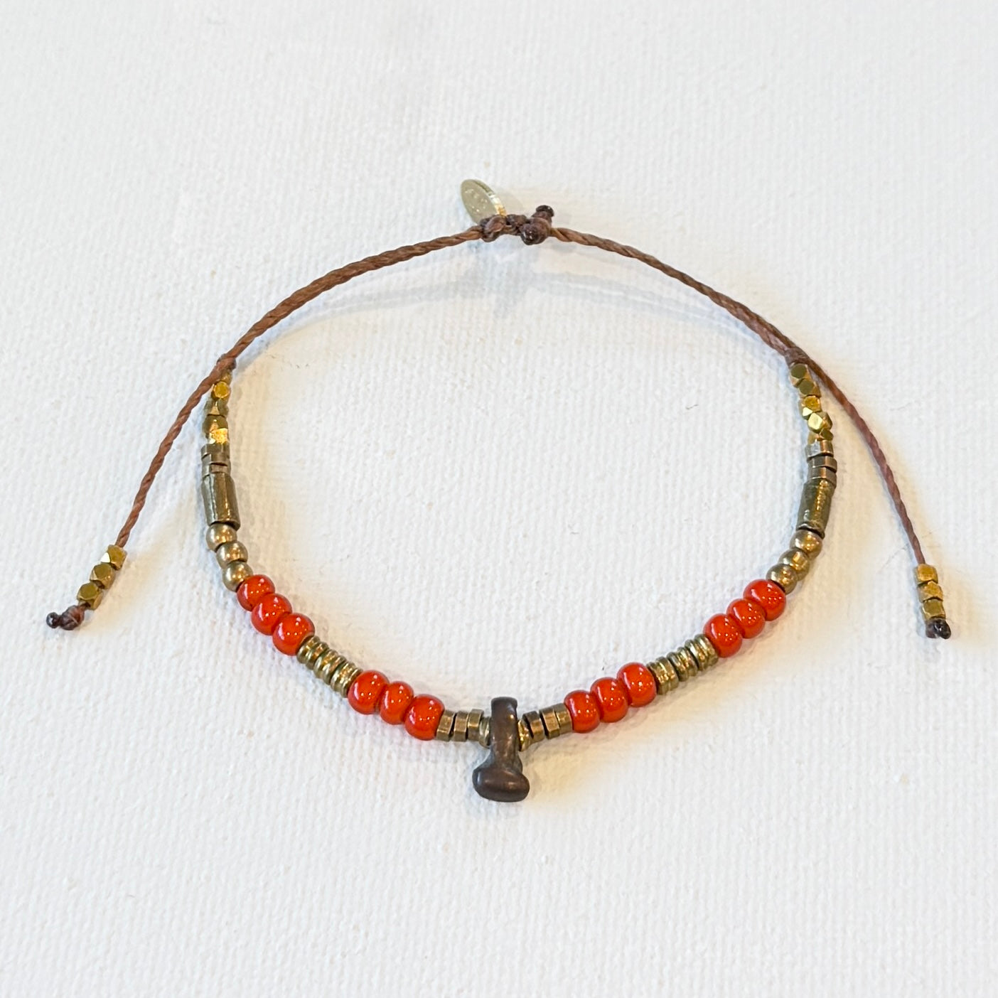 Beaded bracelet with orange and brown beads on a white background. vintage red white heart beads, vintage brass and new brass beads. adjustable in size.