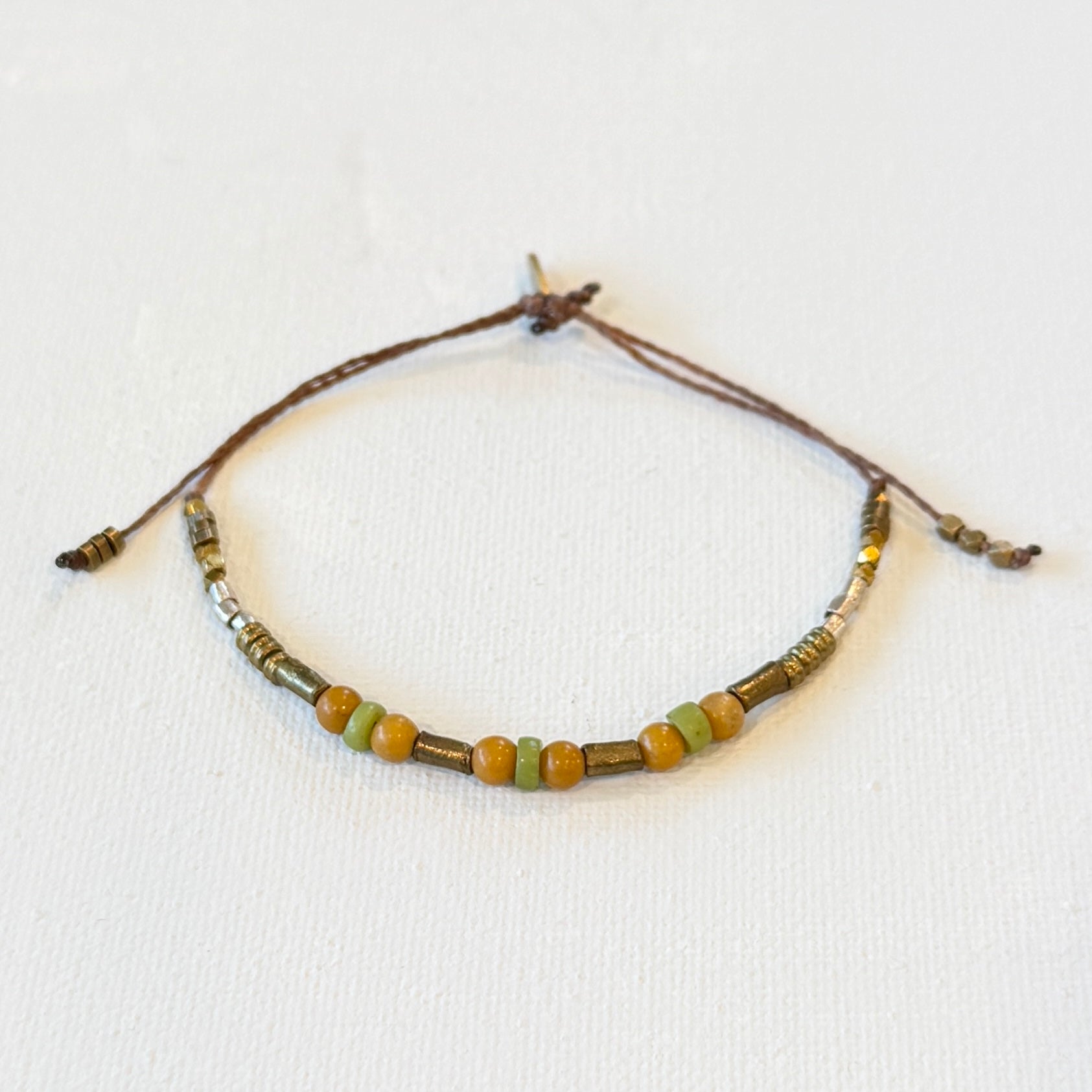 mustard yellow and green vintage glass interlocked with adjustable waxed natural color nylon with brass and silver beads.