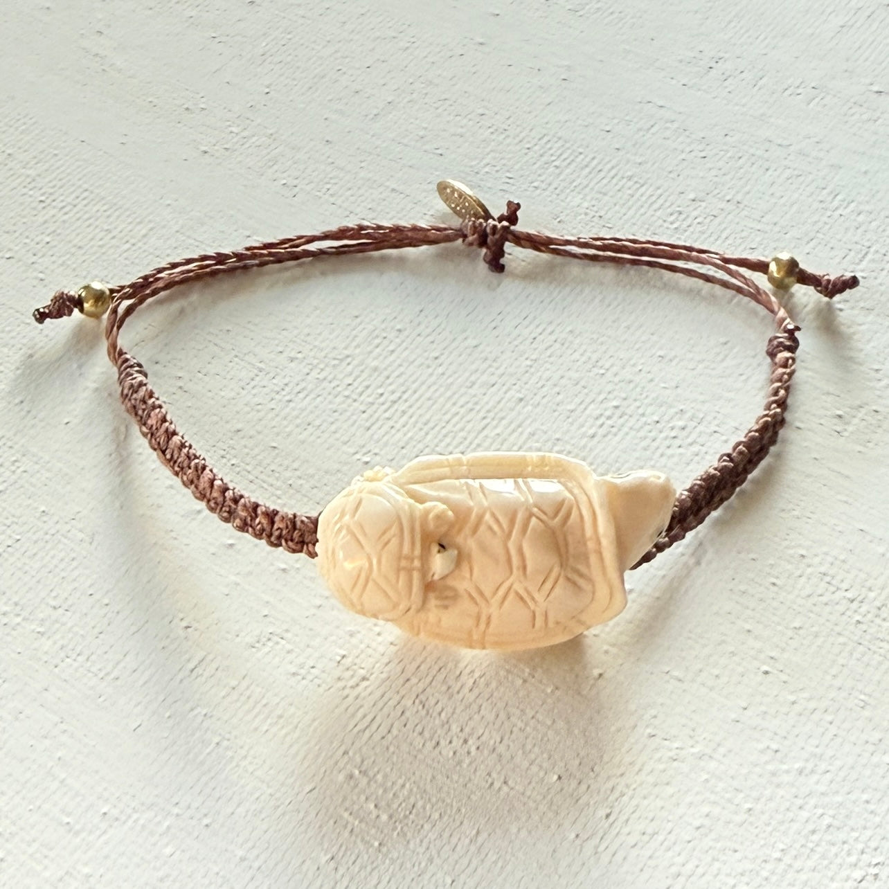 Bracelet with a carved bone pendant on a textured white background