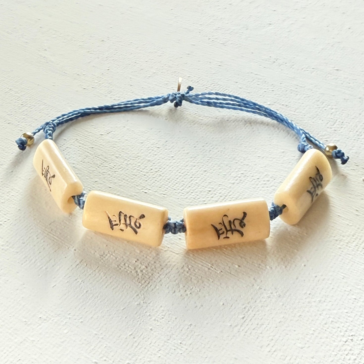 Bracelet with beige beads featuring symbols on a white background