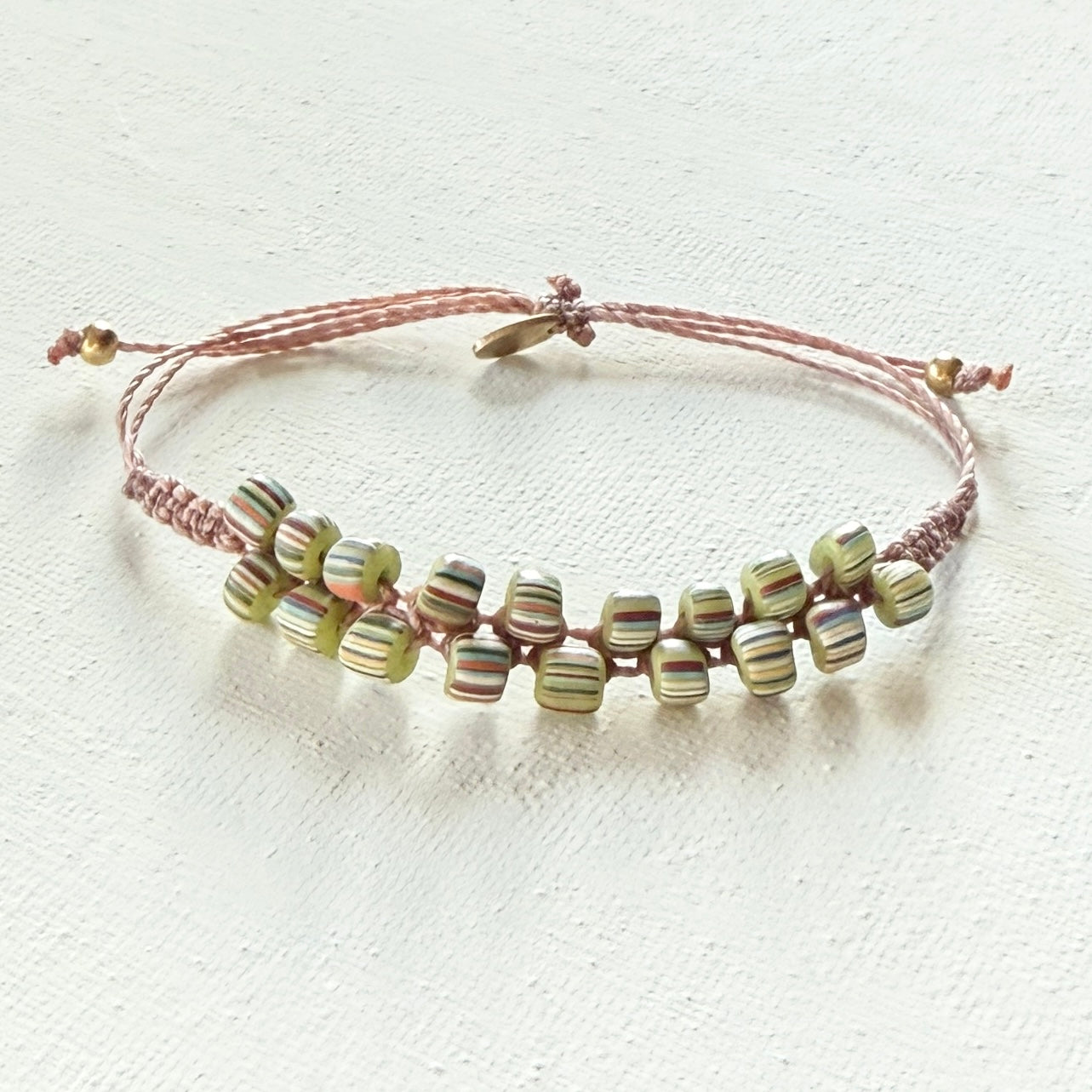 Beaded bracelet with pink cord on a white background